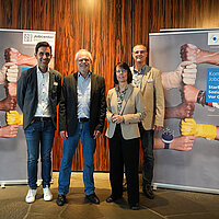 Auf dem Bild sind Christian Fuchs, stellvertretender Leiter des Jobcenters Enzkreis, Hartmut Schölch, Leiter des Jobcenters Enzkreis, Natalie Hohenstein, Leiterin des Pforzheimer Jobcenters und der stellvertretende Leiter des Jobcenters Pforzheim, Reiner Walter, zu sehen, die die Zeitarbeitsmesse im Reuchlinhaus eröffnen. Links und rechts von ihnen stehen zwei Banner der Jobcenter Enzkreis und Pforzheim.