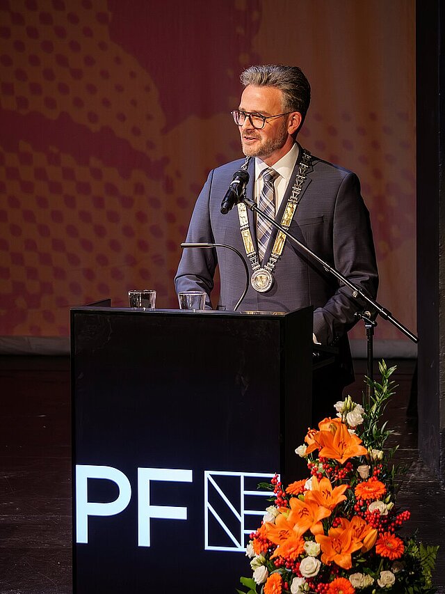 Ein Mann im Anzug steht an einem Rednerpult.