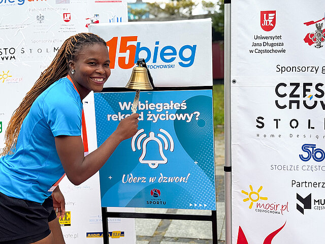 Eine Frau in Sportkleidung läutet an einer Glocke