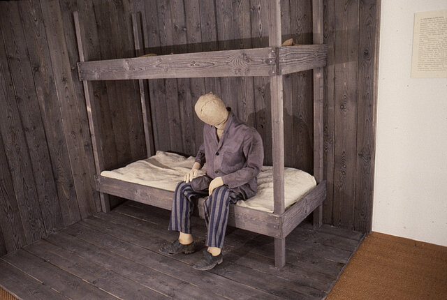 Bild aus der Ausstellung: Puppe in KZ-Häftlingskleidung, Lager-Stockbett