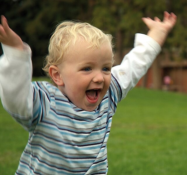 Foto: Rennendes und lachendes Kleinkind im Garten