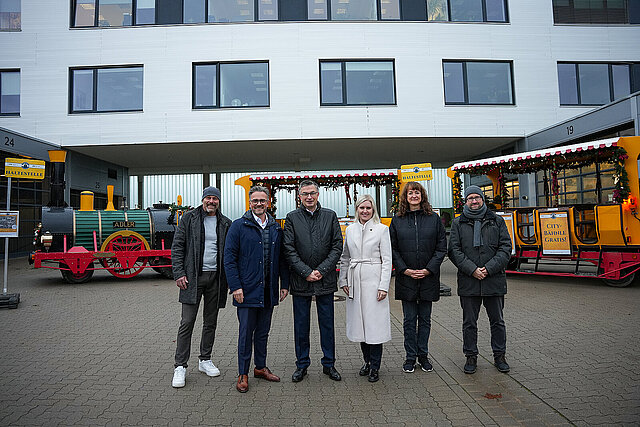 6 Personen stehen vor einem Bähnchen