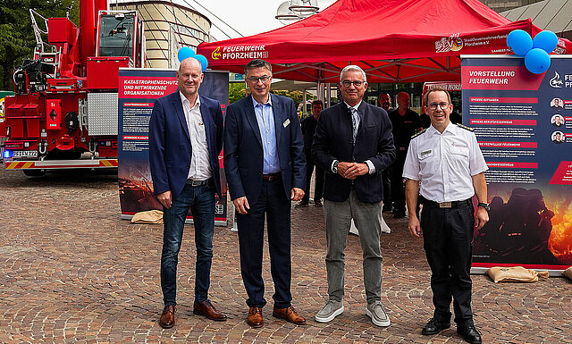 Auf dem Bild sind Erster Bürgermeister Dirk Büscher, WSP-Geschäftsführer Oliver Reitz, Stv. Ministerpräsident und Innenminister Thomas Strobl und Hauptfeuerwehrkommandant Sebastian Fischer vor einem roten Pavillon auf dem Wasinehausplatz sehen. Im Hintergrund ein roter Aufstellkran. 