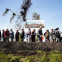 Beim symbolischen Spatenstich für das neue Panoramabad auf dem Wartberg sieht man viele Menschen, darunter Oberbürgermeister Peter Boch, die mit Spaten Erde in die Luft werfen.