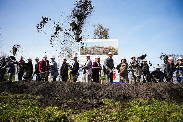 Beim symbolischen Spatenstich für das neue Panoramabad auf dem Wartberg sieht man viele Menschen, darunter Oberbürgermeister Peter Boch, die mit Spaten Erde in die Luft werfen.