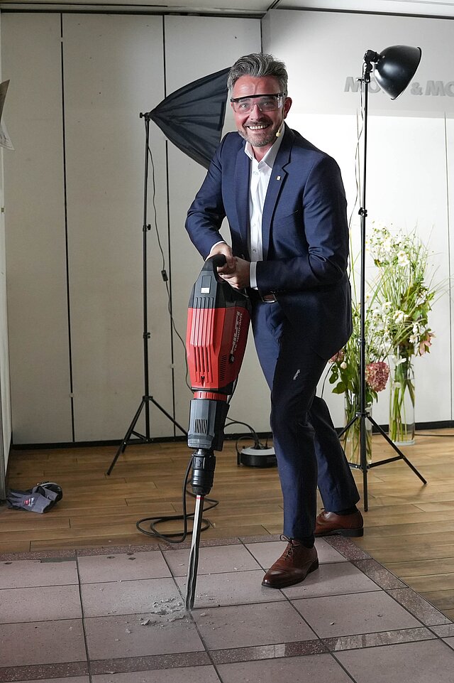 Ein Mann im Anzug bedient einen Presslufthammer