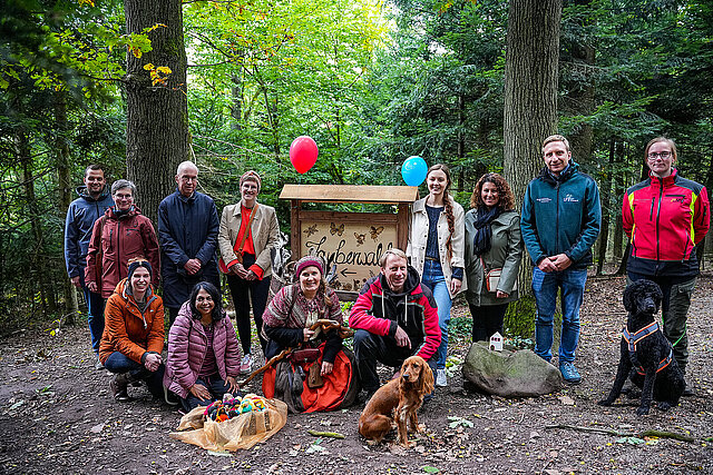 Auf dem Bild ist eine große Gruppe von Menschen vor einem Schild mit der Aufschrift Zauberwald zu sehen.