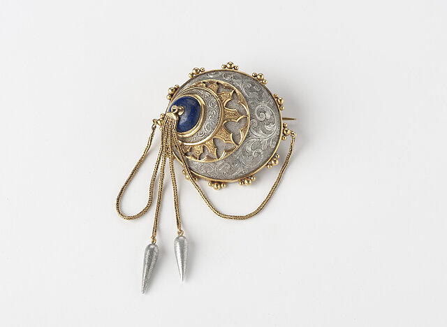 Eine runde Brosche in Silber und Gold mit zwei Perlen an dünnen Ketten