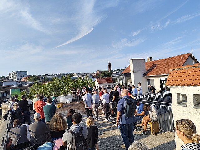 Viele Menschen auf einer sonnigen Dachterrasse