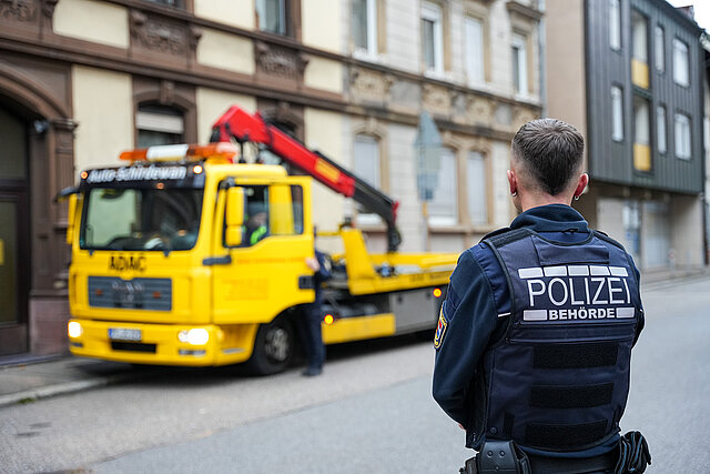 Ein Mann in Uniform von der Polizeibehörde steht vor einem gelben Laster