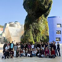 Ein Gruppe Menschen vor einer begrünten Skulptur.