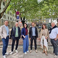 6 Personen stehen vor grünen Bäumen