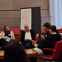 Auf dem Bild ist der Pforzheimer Bürgermeister Frank Fillbrunn zu sehen, wie er mit Schülern im Gespräch ist.