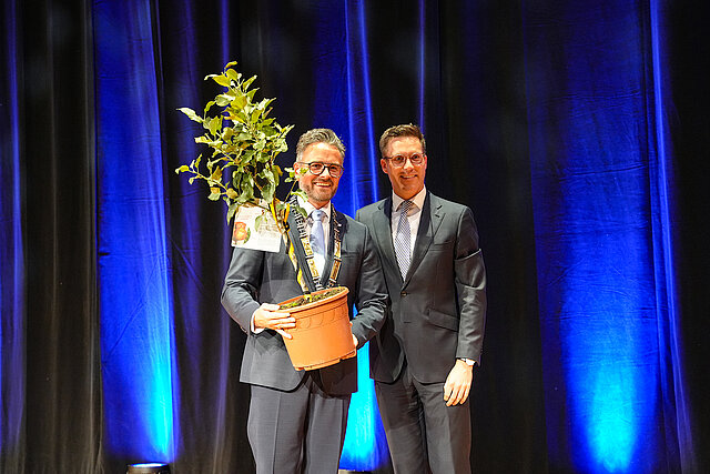 Manuel Hagel und Oberbürgermeister Peter Boch mit einem kleinen Apfelbaum