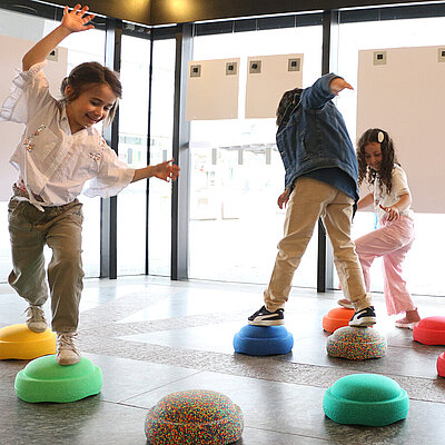 Kinder, die auf Schaumstoff Steinen im Stadtlabor, Rathauspavillon spielen.