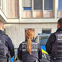 Farbfoto: stehend in einer Reihe rückwärts: Zollbeamter, Polizeibeamtin, Beamter der Polizeibehörde