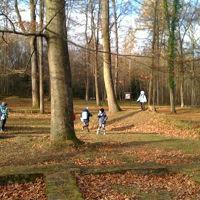 Kinder laufen zwischen den alten Mauerresten im Wald