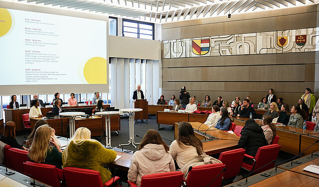 Sozialbürgermeister Frank Fillbrunn steht an einem Podium und begrüßt die Kundinnen sowie Partnerinnen und Partner zu Beginn des Perspektiventags für Migrantinnen.