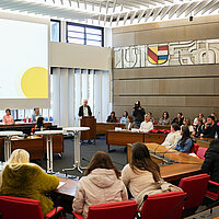 Sozialbürgermeister Frank Fillbrunn steht an einem Podium und begrüßt die Kundinnen sowie Partnerinnen und Partner zu Beginn des Perspektiventags für Migrantinnen.