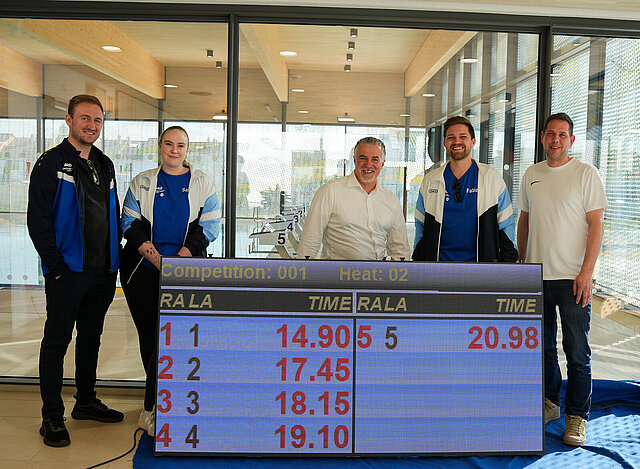 Björn Kohler, Kampfrichterobmann beim SSV Huchenfeld, Sabrina Gohminger, 2. Vorsitzende beim SSV Huchenfeld sowie Ralf Gremmer, Vorsitzender SSC Sparta Pforzheim 1929, Fabian Sowa, Vorsitzender SSVH und Ingo Wüst vom SSC Sparta 1929 Pforzheim stehen hinter einer digitalen Zeitmesstafel.