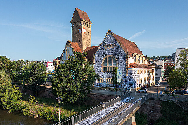 Farbfoto: EMMA Kreativzentrum von Außen mit Portraits auf der Fassade und dem Gehweg