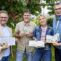 Vier Personen, die alle kleiner Kinderbücher in der Hand halten.