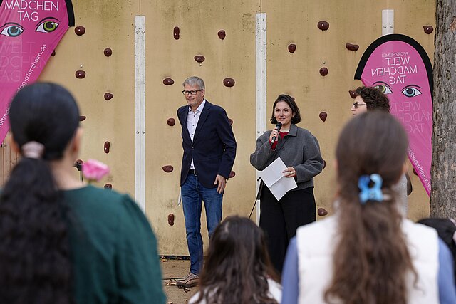 Farbfoto: Der Schulleiter der Nordstadtschule Oliver Hesselschwerdt begrüßt gemeinsam mit der städtischen Gleichstellungsbeauftragten Nur Bakkar die Teilnehmerinnen und Teilnehmer des Weltmädchentags. 