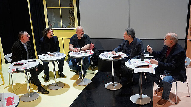 farbiges Gruppenbild: alle Personen sitzen an runden Tischen im Halbkreis