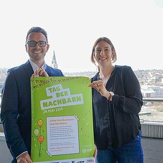 Oberbürgermeister Peter Boch und Susanne Wacker, Ansprechpartnerin bei der Stadtverwaltung, halten Plakat zum Tag der Nachbarn