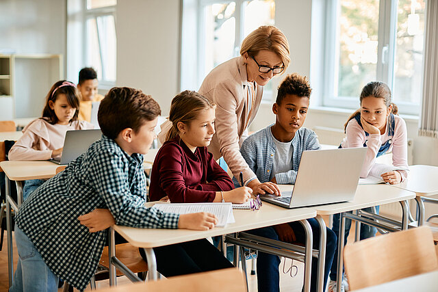 Eine Gruppe von Grundschülern hat mit ihrer Lehrerin im Klassenzimmer Computerunterricht. - copyright:iStock/Drazen Zigic