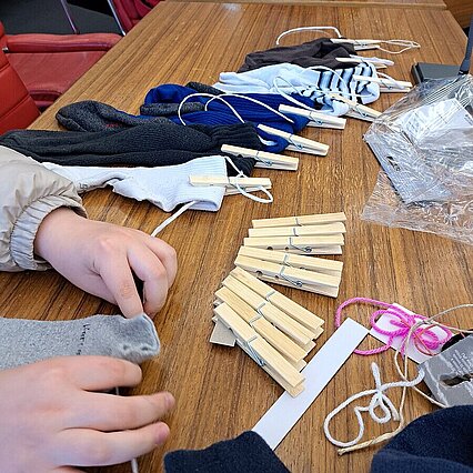 Auf dem Foto sieht man die Hände einer Person, die mit Holzwäscheklammern Socken auf einer Leine befestigt. - copyright:Stadt Pforzheim