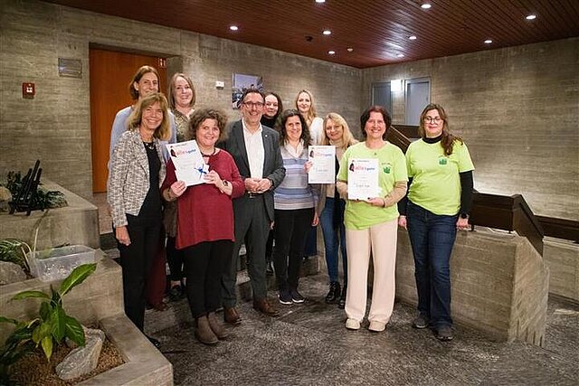 Eine Gruppe von Personen, einige halten eine Urkunde in den Händen