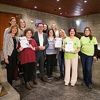 Eine Gruppe von Personen, einige halten eine Urkunde in den Händen