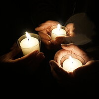 Bild von drei Kerzen, die von drei Händen gehalten werden