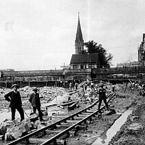 Schwarz-Weiß-Foto 1910: Bauarbeiter an der Nagold, im Hintergrund die Auerbrücke. - copyright:Stadtarchiv Pforzheim – Institut für Stadtgeschichte, S1-3-2-R-53