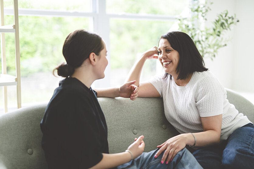 mother with teen girl, having great time speaking on sofa