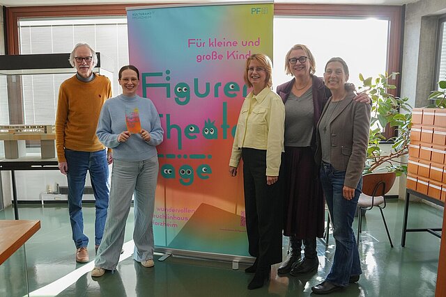 Fünf Personen vor einem Roll-Up mit der Aufschrift "Figurentheatertage" 