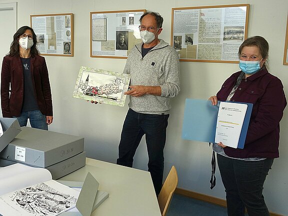 Karikaturist Gerald Manz, Sammlungsarchivarin Andrea Binz-Rudek (r.) und Archivleiterin Klara Deecke mit dem neuen Archivbestand