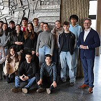 Viele Menschen vor einer grauen Steinwand. 