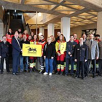 Eine große Gruppe an Menschen, die eine große gelbe Karte halten. 