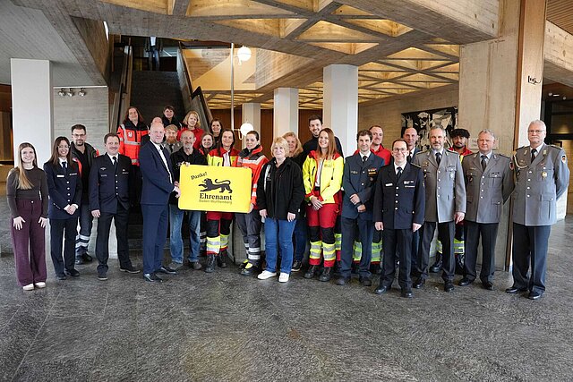 Eine große Gruppe an Menschen, die eine große gelbe Karte halten. 