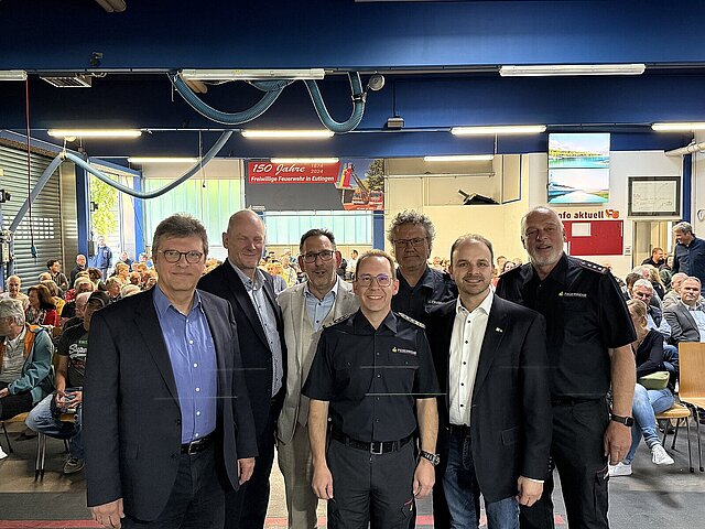 Ein Gruppenbild mit Verantwortlichen, die in einer Halle der Feuerwehr über die zukünftige Feuerwache Ost in Pforzheim informieren. 
