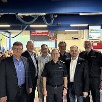 Ein Gruppenbild mit Verantwortlichen, die in einer Halle der Feuerwehr über die zukünftige Feuerwache Ost in Pforzheim informieren. 