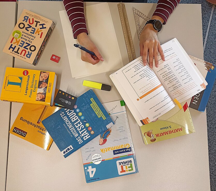 Fotografie von einem Arbeitsplatz auf dem Schulmaterial liegt und sich jemand Notizen macht - copyright: Stadtbibliothek Pforzheim - Ersteller: Sabrina Marek