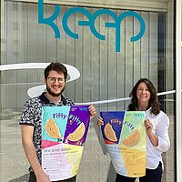 Geschäftsführer Elias Weigel und Projektleiterin Carmen Klein stehen vor der keep Geschäftsstelle mit Plakaten in der Hand..