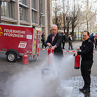 Schulbürgermeister Frank Fillbrunn (links) und Feuerwehrkommandant Sebastian Fischer löschen mit zwei Feuerlöschern ein Übungsfeuer beim Aktionstag.
