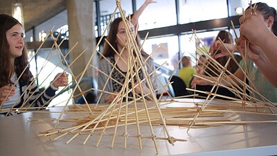Farbfoto: Jugendliche sitzen am Tisch und basten mit Bambusstäben