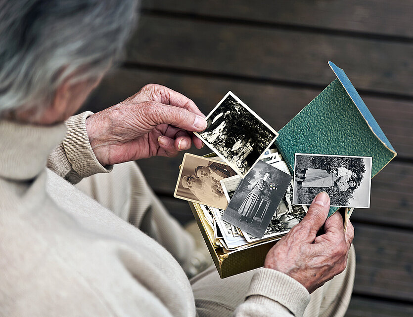 Seniorin hält alte Fotos in der Hand - copyright: AdobeStock - Ersteller: AdobeStock