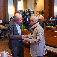 Auf dem Bild ist Sozialbürgermeister Frank Fillbrunn zu sehen, wie er Frank Johannes Lemke vom Leitungsteam der Vesperkirche Pforzheim die traditionelle Spende der Stadt überreicht.