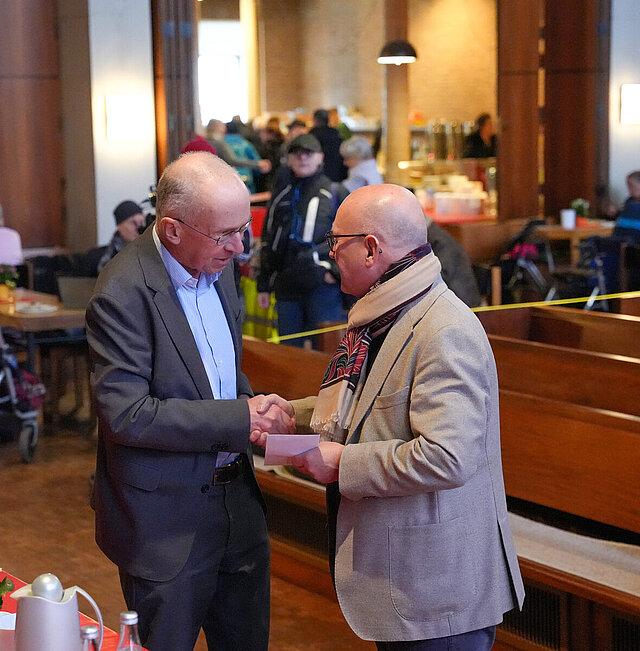 Auf dem Bild ist Sozialbürgermeister Frank Fillbrunn zu sehen, wie er Frank Johannes Lemke vom Leitungsteam der Vesperkirche Pforzheim die traditionelle Spende der Stadt überreicht.